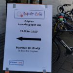 Foto van een bord bij de Uitwijk met daarop de volgende tekst: Repaircafe Zutphen is vandaag open van 13:00 tot 16:00. Buurthuis de Uitwijk, Brink 116 Zutphen